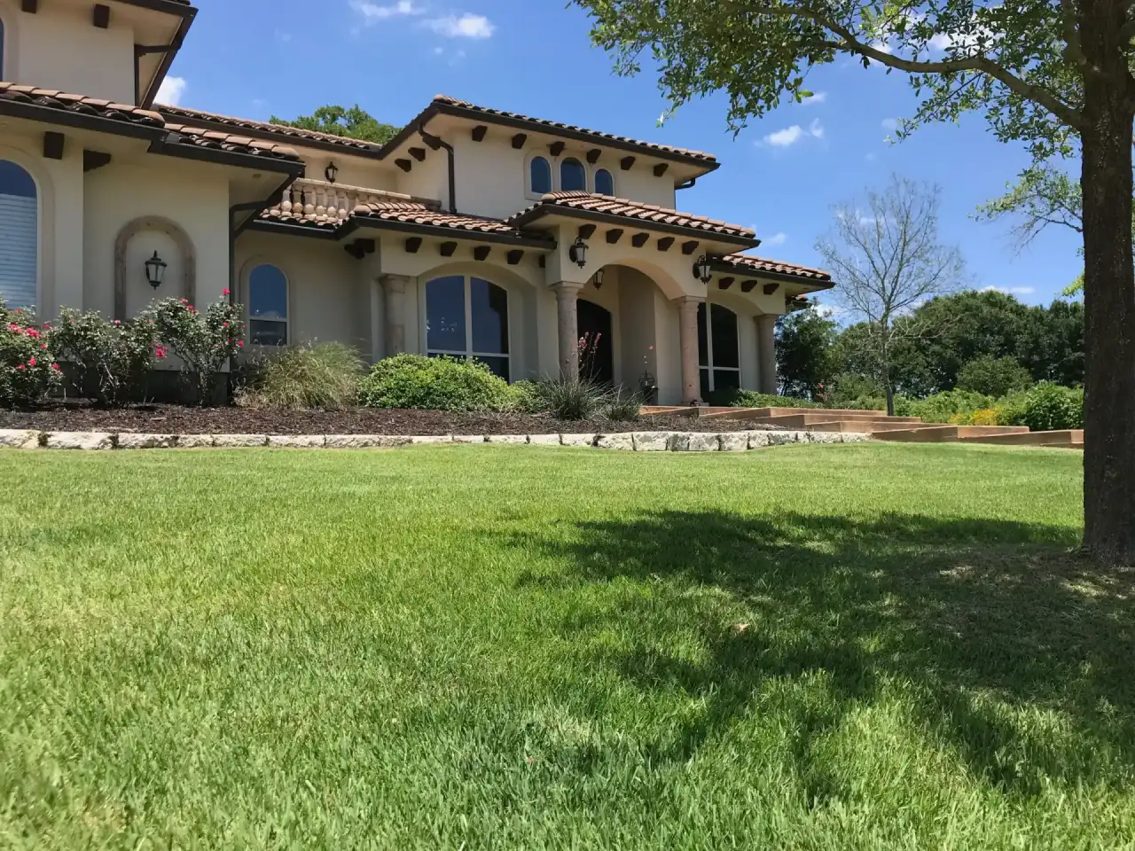 Freshly mowed green lawn in front of a Mediterranean-style College Station home