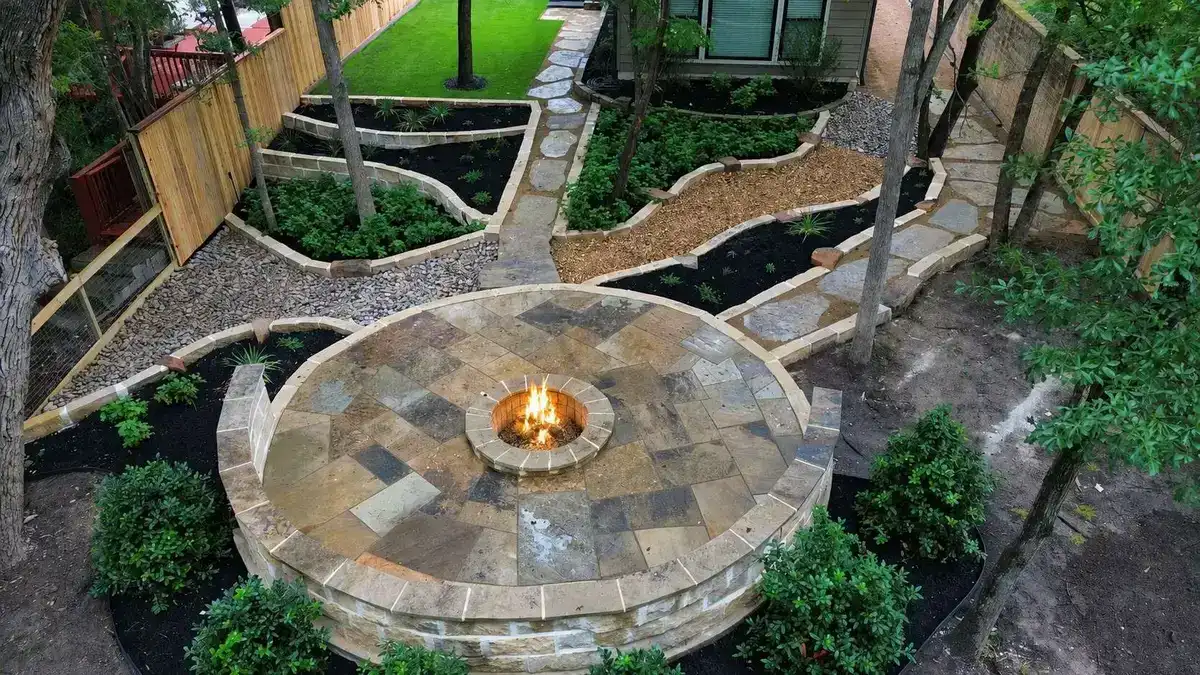Round stone patio with a lit fire pit, connected by curving walkways