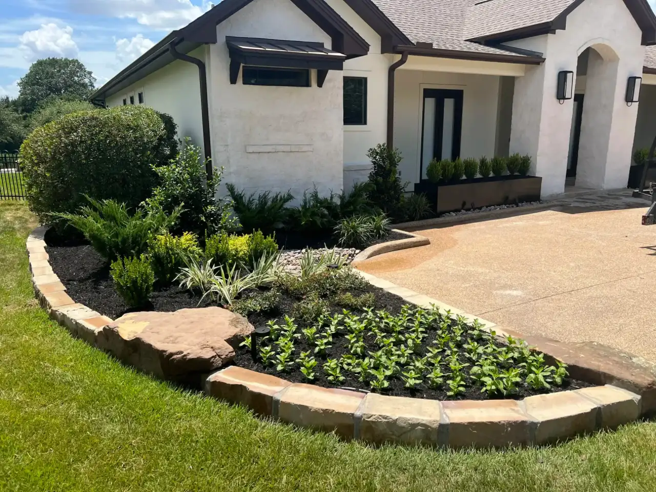 Curved stone-bordered bed with fresh plantings across a home's front yard