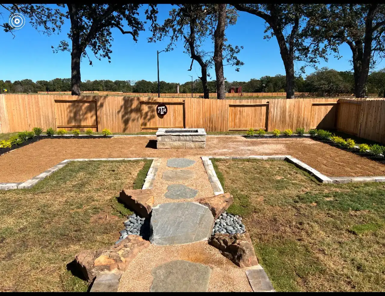 Flagstone walkway crossing a fenced backyard toward a stone water feature