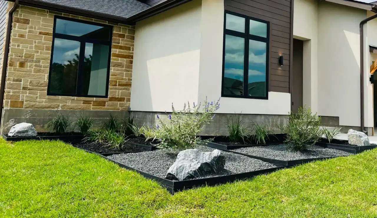 Ornamental grasses and boulders set in dark mulch beds along a modern home