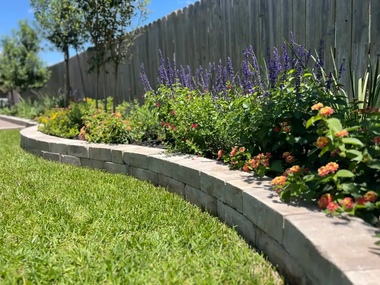Bryan TX residential landscape with stacked stone garden wall and integrated plantings showing the kind of refresh and redesign work Greener Lawnscapes delivers across College Station properties